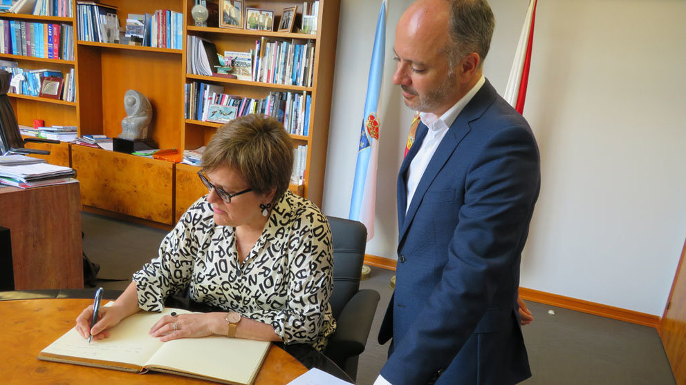 La secretaria de Estado, Ángeles Heras, escribiendo en en el libro de firmas de Zona Franca ante el delegado David Regades.