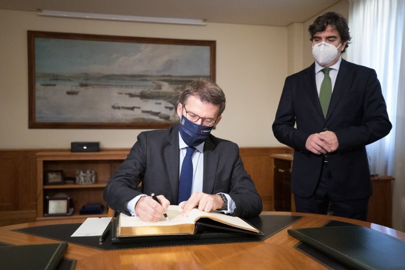 Núñez Feijóo firmando en el libro de honor de la Autoridad Portuaria de A Coruña en presencia de su presidente, Martín Fernández.