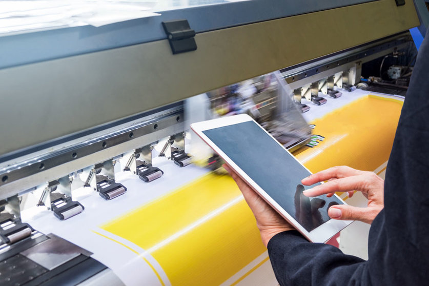 Technician touch control tablet on format inkjet printer during yellow vinyl paper